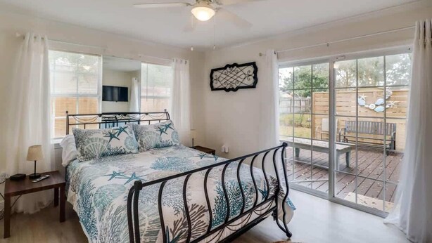 Un dormitorio con cama, ventilador de techo, ventana y vistas al exterior.