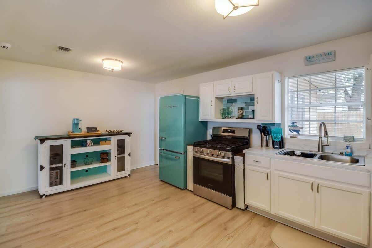 Een keuken met witte kastjes, een blauwgroene koelkast, een fornuis en een spoelbak.