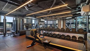 Ein Fitnessraum mit Trainingsgeräten, einer Gewichtbank und einer Hantelbank.