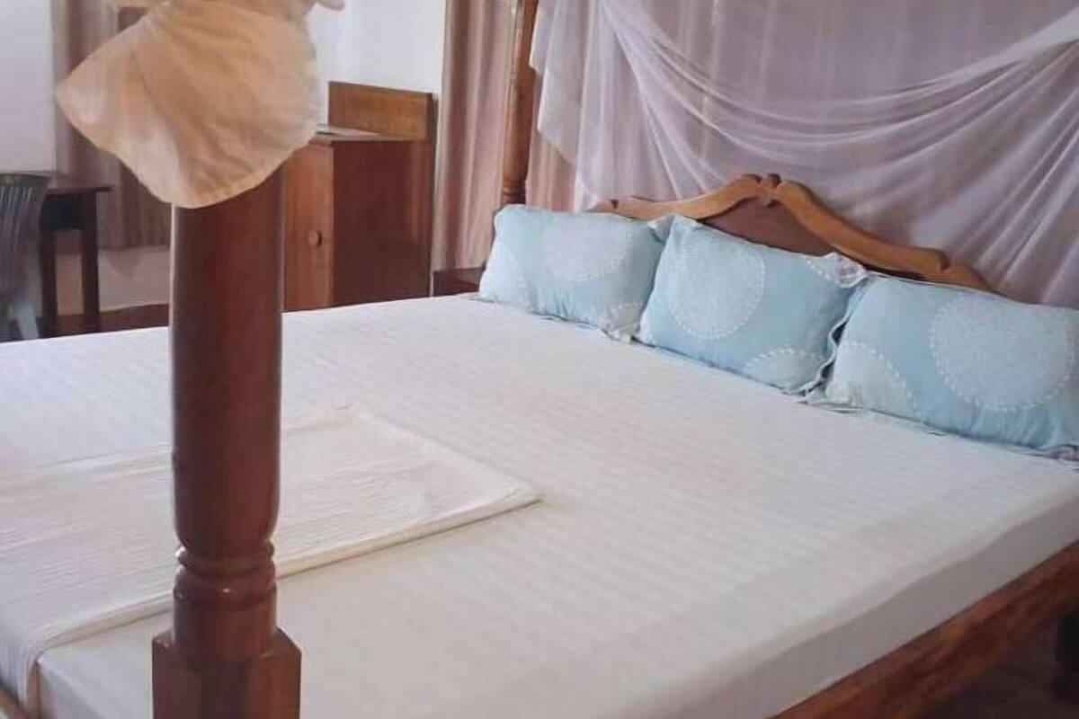 Una cama con dosel, cabecera de madera y almohadillas azul claro.