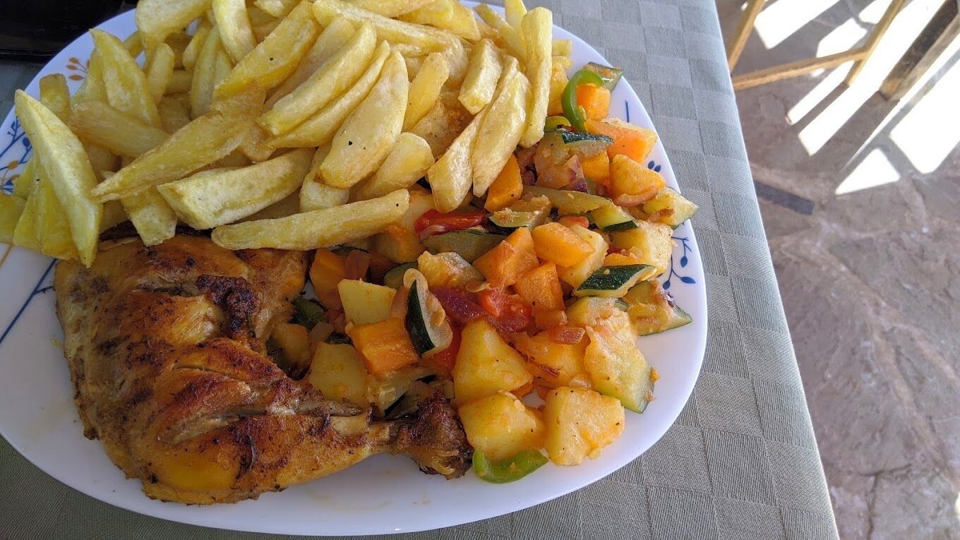 A plate with a grilled chicken leg, French fries, and a vegetable medley.