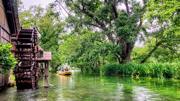A river with a wooden water wheel and a yellow boat.