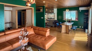 A modern living room with a sofa, a dining area, and a kitchen.
