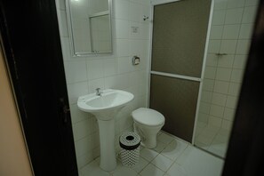 Un baño con lavamanos, inodoro y zona de ducha.