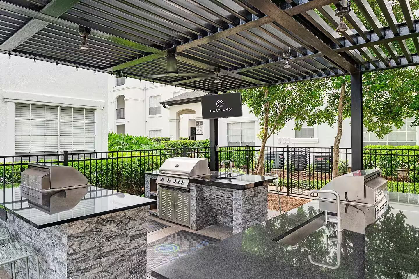 An outdoor patio with a grill, seating, and a sign for Cortland.