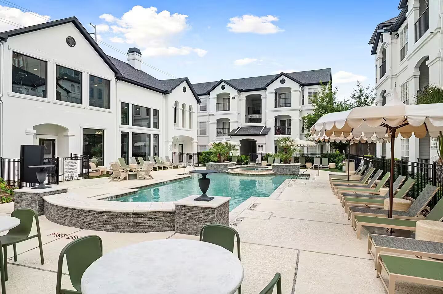 A pool area with lounge chairs and a dining table.