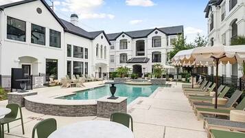 A pool area with lounge chairs and a dining table.