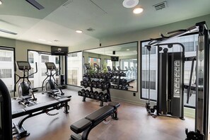 A gym with cardio machines, dumbbells, a bench, and mirrors. - Chic 2BR Apartment Minutes to Montrose (Houston)