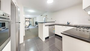 Una cocina moderna con lavavajillas integrado, estufa y un comedor visible al fondo.