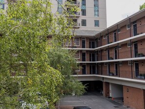 Un edificio residencial de varios pisos con un patio central, balcones y un estacionamiento.
