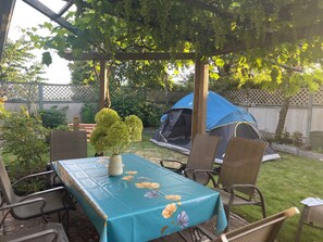 A covered patio with a table, chairs, a tent, and a garden. - Anna's cozy house (Delta)