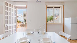 A dining area with a table set for four, white chairs, a white refrigerator, and a window with a view of the outside. - Buena Vista - Sea Oasis Residence (Salve)