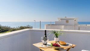 A balcony with a table set for two, a bottle of wine, a bowl of fruit, and a potted plant. - Buena Vista - Sea Oasis Residence (Salve)