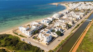 An aerial view of a coastal residential area with white buildings, a beach, and a river. - Buena Vista - Sea Oasis Residence (Salve)