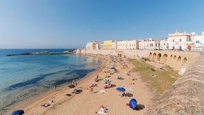 Una playa con aguas cristalinas, un paseo marítimo y edificios a lo largo de la costa.