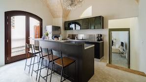 Una cocina moderna con una isla central, taburetes de bar y una lámpara de araña.