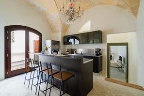 Una cucina moderna con isola centrale, sgabelli da bar e un lampadario.