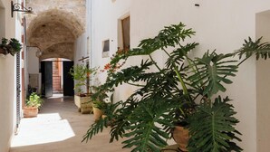 Un couloir étroit, surmonté d’une arche en pierre, agrémenté de plantes en pot et doté d’un sol carrelé.