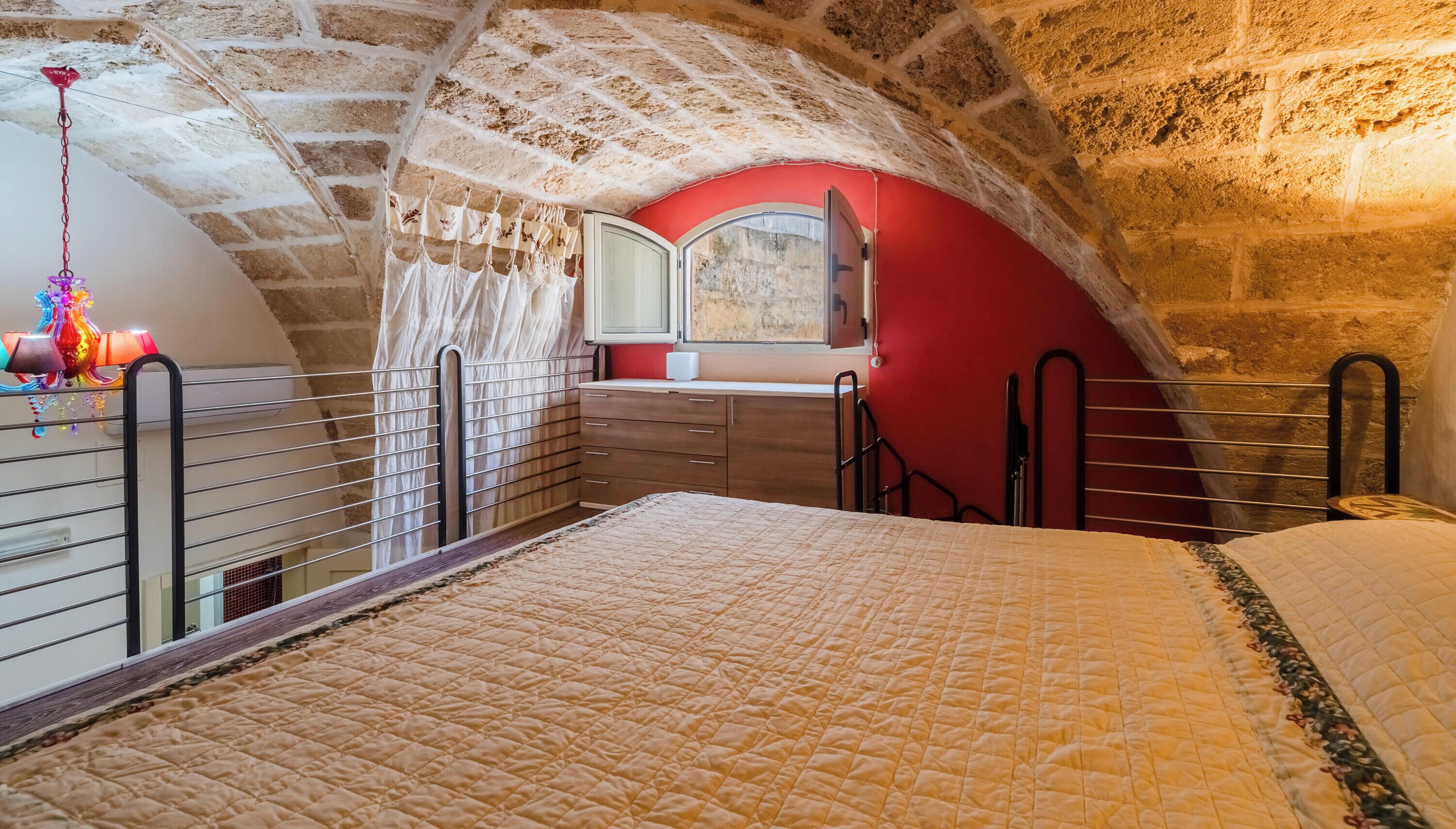 Ein Schlafzimmer mit einem Bett, einem Schminktisch, einem Spiegel und einer roten Wand.