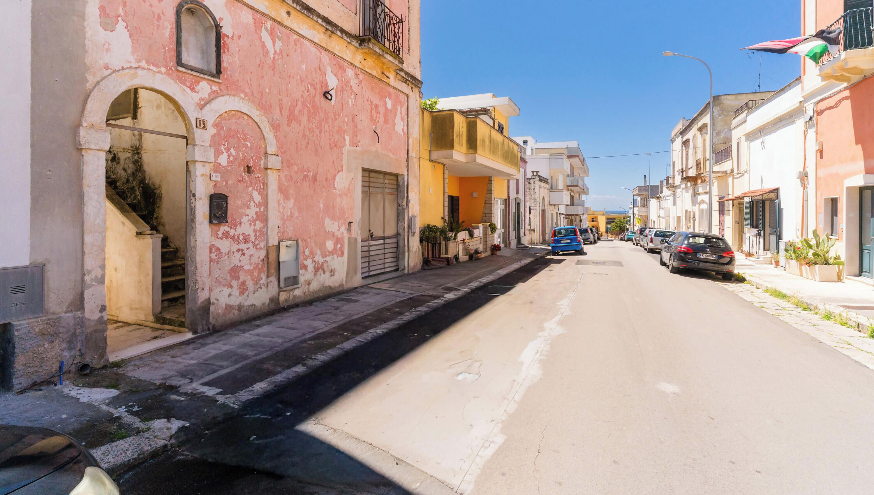 Una calle estrecha bordeada de edificios, algunos con balcones y otros con accesos directos.