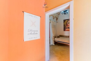 Una stanza con un letto, un quadro e un cartello al muro.