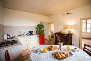 Eine Küche mit Gasherd, Spüle, Esstisch mit Frühstücksgebäck und einer Pflanze.