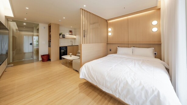 A modern hotel room with a large bed, a small table, a kitchenette, and a bathroom. - Tongyeong Dongpirang Stay.h (Tongyeong)