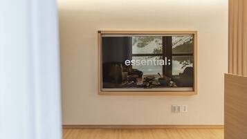 A framed photograph on a wall with a window reflection, a power outlet, and a wooden floor.