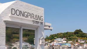 A white building with a sign reading 'Dongpiring Stay Hotel.' - Tongyeong Dongpirang Stay.h (Tongyeong)