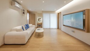 A modern living room with a sofa, coffee table, and a large TV screen. - Tongyeong Dongpirang Stay.h (Tongyeong)
