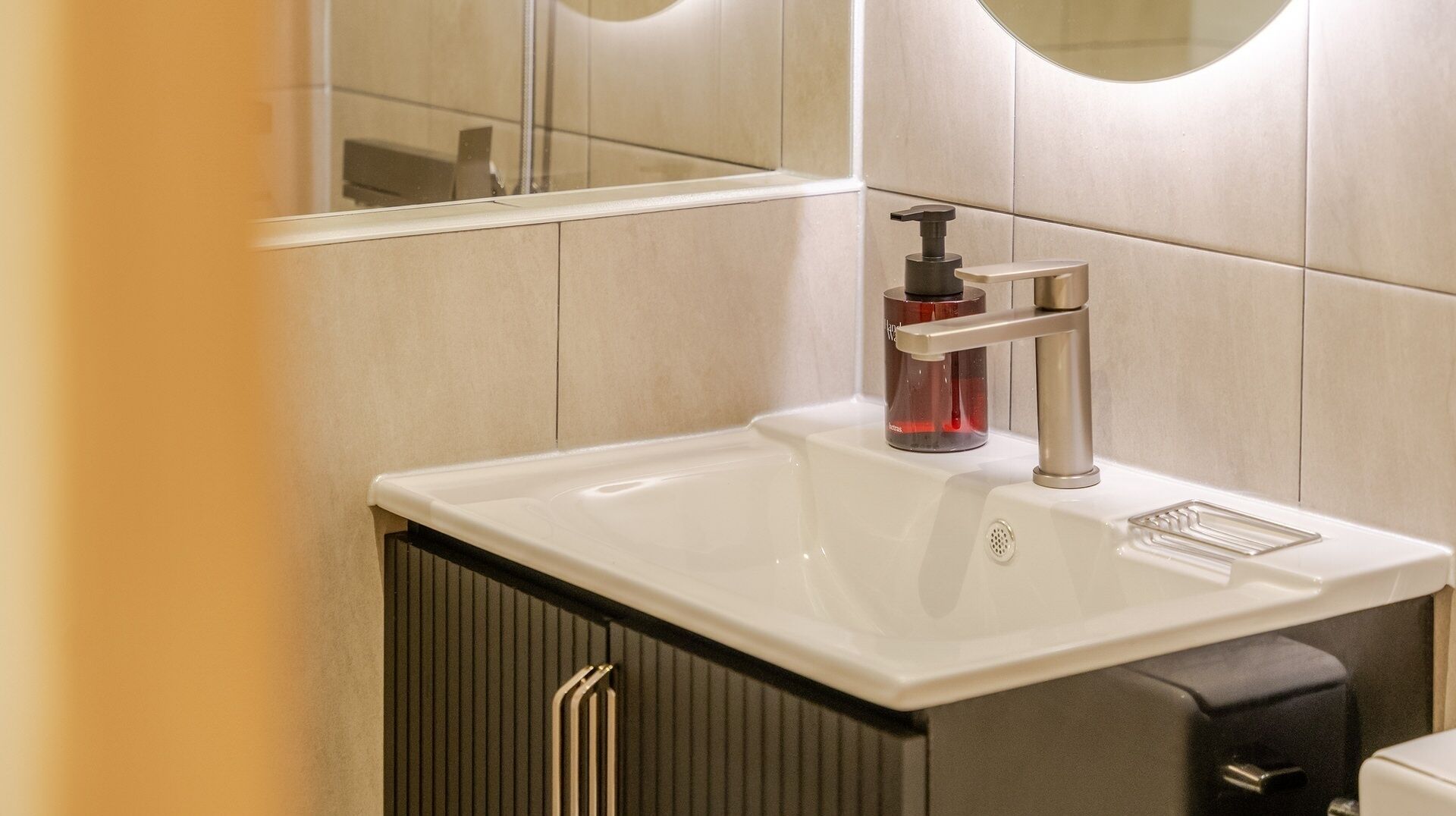 Un baño con un lavamanos blanco, un grifo moderno y un espejo.