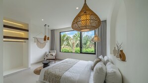 Un dormitorio moderno con una cama grande, una silla colgante y vistas a zonas verdes por la ventana.