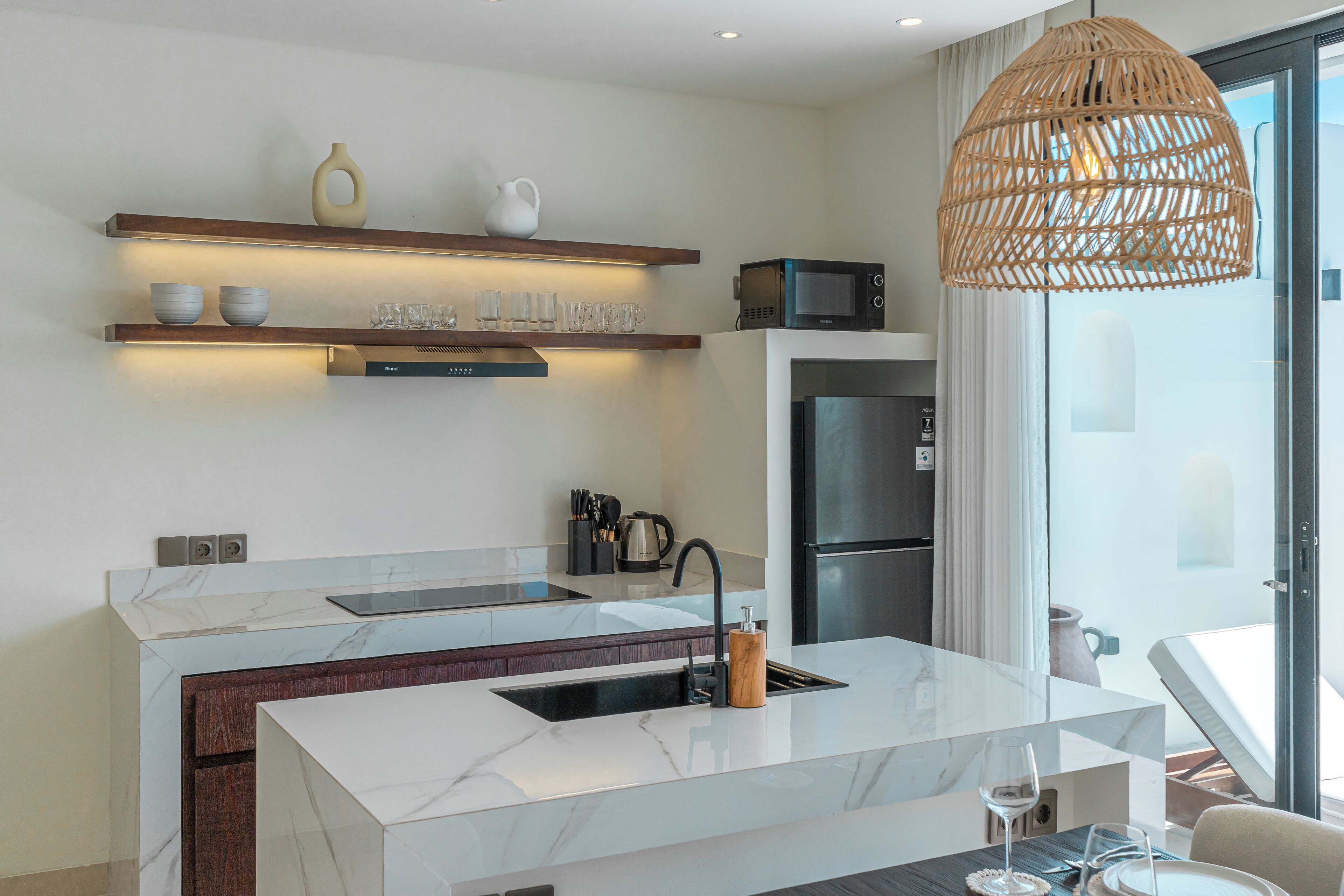 A modern kitchen with a marble countertop, built-in appliances, and a dining area with a table and chairs.