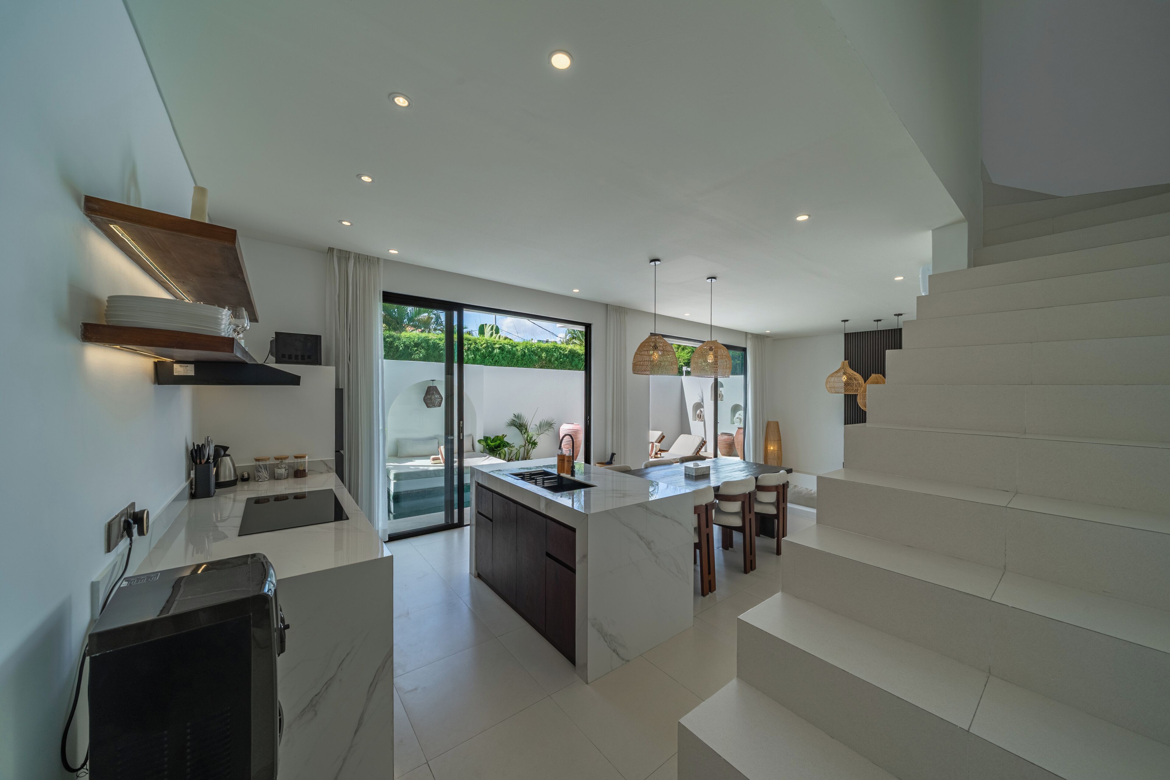 Una cocina moderna con una isla central, electrodomésticos integrados y vistas a un balcón.