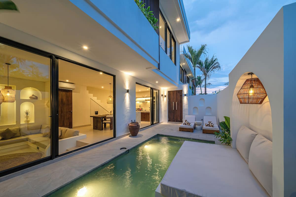 Une maison moderne dotée d’une piscine, d’un espace salon extérieur et d’un escalier menant à l’étage supérieur.
