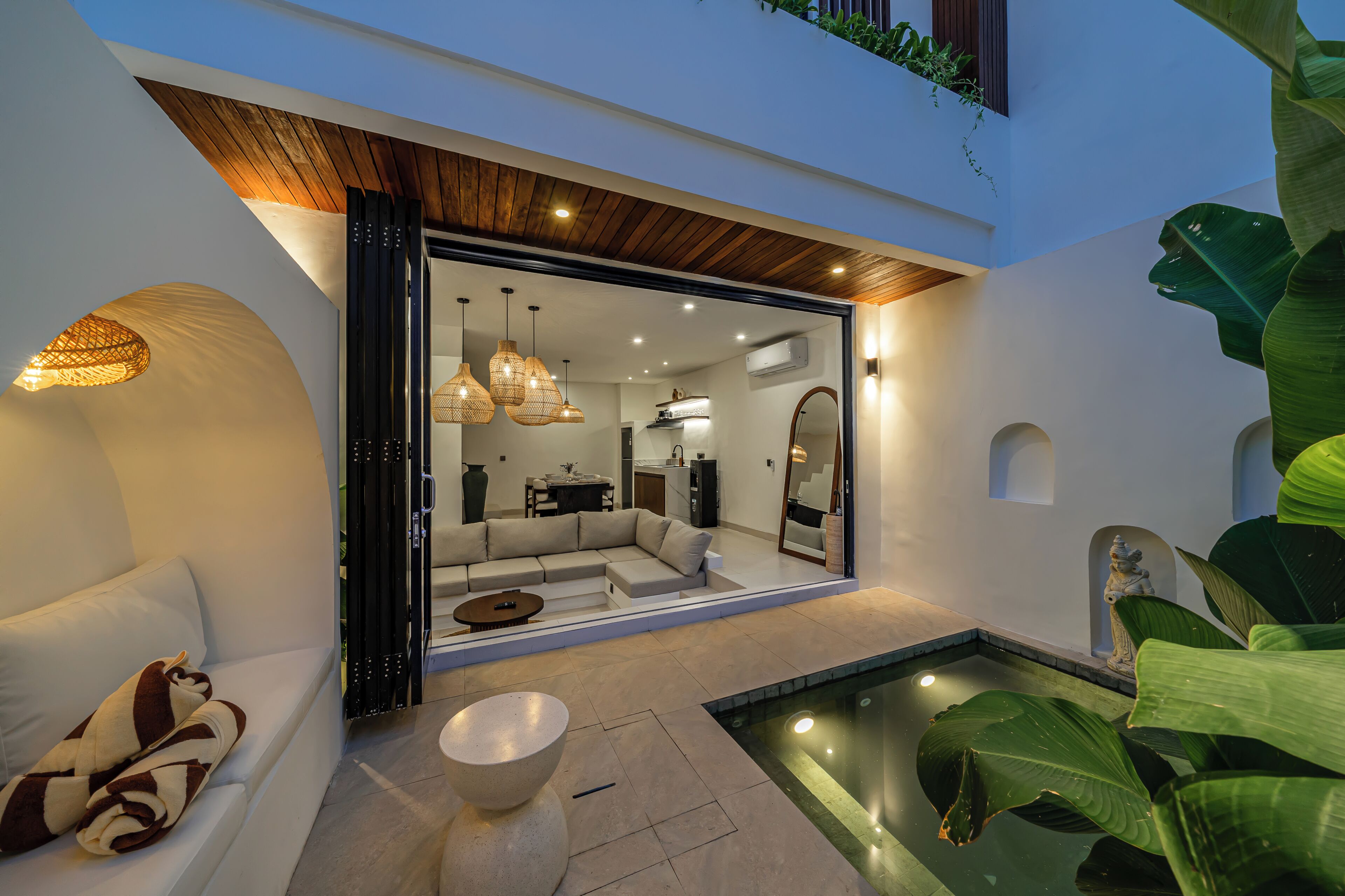 Un interior con un sofá, una mesa de centro, una zona de comedor y una piscina.