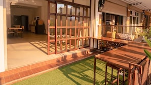 Un edificio moderno con amplios ventanales correderos, un patio con mesa de madera y un césped verde.