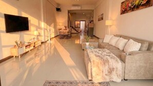 Una sala de estar moderna con un sofá, un televisor de pantalla plana, una mesa de centro y una alfombra estampada.