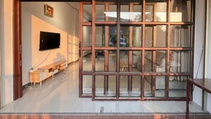 Un interior moderno con un televisor montado en la pared, un banco de madera y un amplio separador de vidrio.