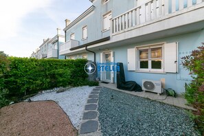 Un edificio residenziale con vialetto in pietra, giardino e un condizionatore d'aria a vista.