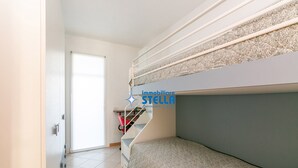 A room with bunk beds, a staircase, and a door leading to another room. - Antenore [relaxation with swimming pool] (Lido di Jesolo)