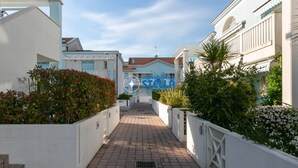 A pathway leading to a building with a white facade and a blue sky. - Antenore [relaxation with swimming pool] (Lido di Jesolo)