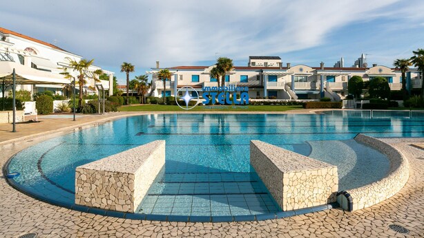 A swimming pool with stone tiles, surrounded by a paved area and palm trees. - Antenore [relaxation with swimming pool] (Lido di Jesolo)