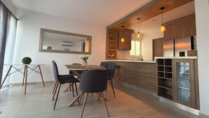 Une cuisine moderne avec des meubles en bois, un coin repas comprenant une table et des chaises, et un éclairage suspendu.