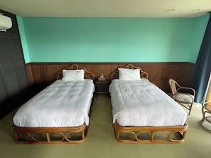 Quarto duplo com duas camas de solteiro, cabeceiras de madeira, mesa de cabeceira e uma cadeira.