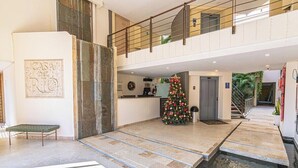 A spacious lobby with a Christmas tree, a bench, and a staircase leading to an upper level. - Designer apartment with pool and private balcony (Santa Marta)