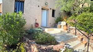 A stone-walled building with a door, a red garden hose, and a stone staircase leading to a door. - Paradise on the sea (Théoule-sur-Mer)