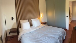 A bedroom with a bed, pillows, a nightstand, a wall-mounted light, and a sliding door. - Paradise on the sea (Théoule-sur-Mer)