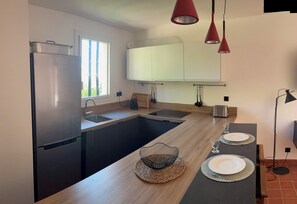 Eine moderne Küche mit einem Edelstahl-Kühlschrank, Holz Arbeitsplatten, einer eingebauten Spüle und einem Essbereich mit zwei Tellern und Gläsern.
