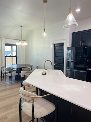 Una cocina moderna con una isla central, armarios negros y un refrigerador de acero inoxidable.